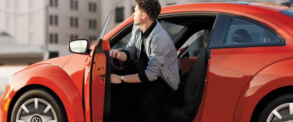 2019 Volkswagen Beetle A man getting out of an orange VW Beetle