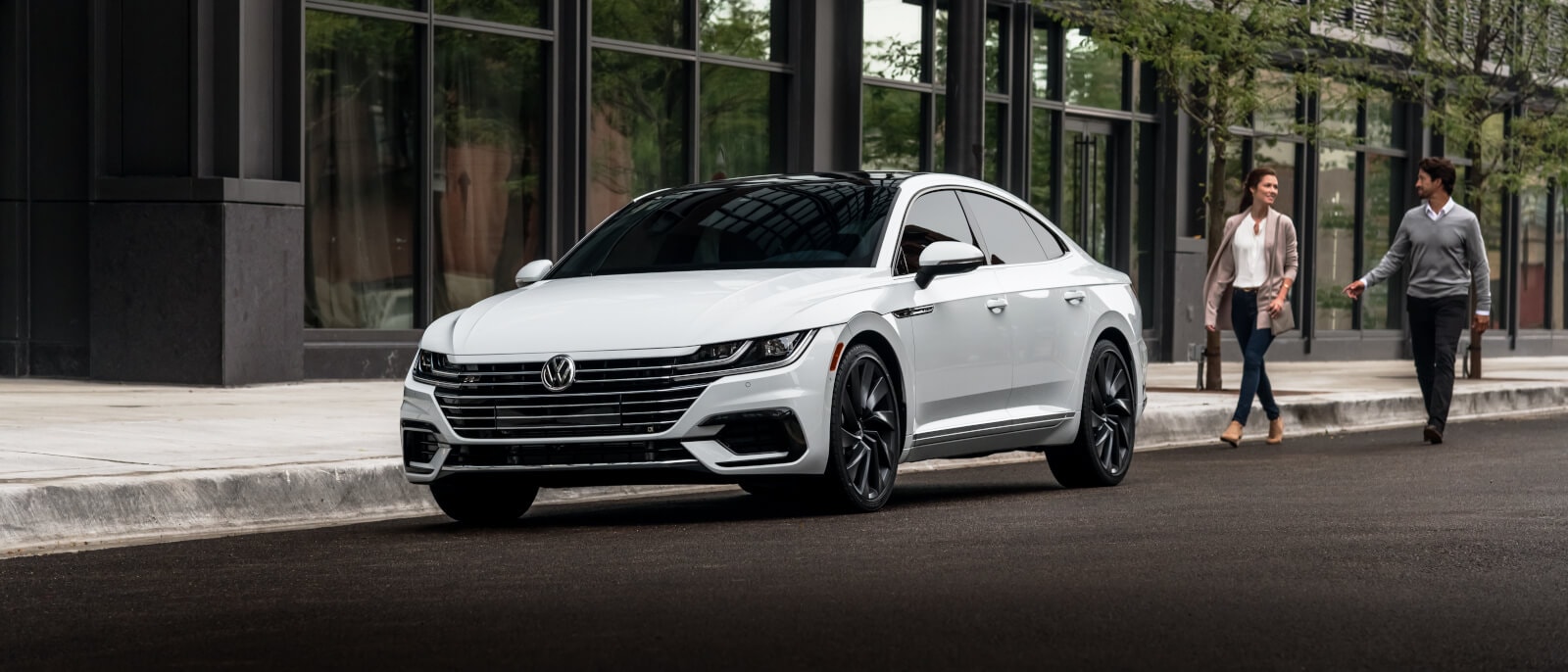 A white VW Arteon parked on the street of a city