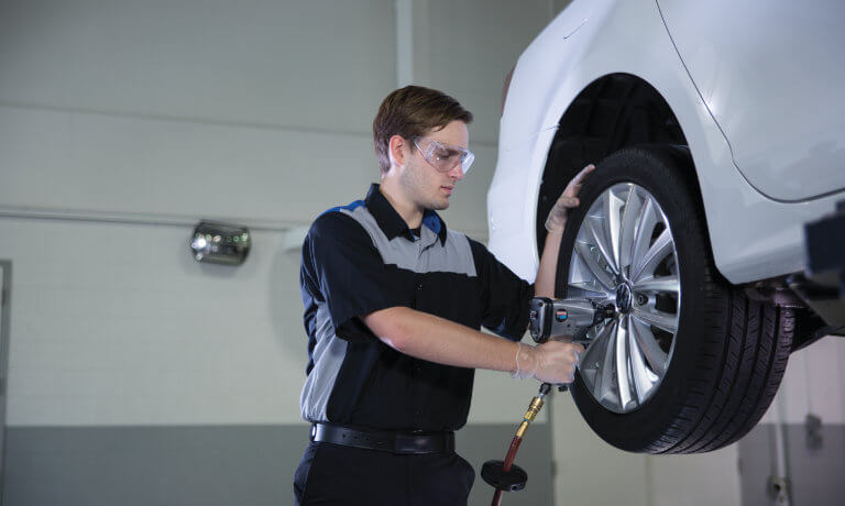 VW service technician working on a tire