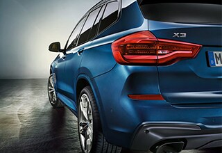 Back left taillight view of blue BMW X3 parked on concrete