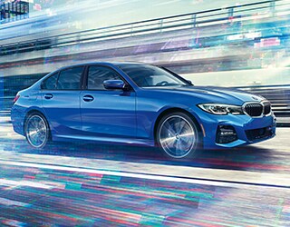 Blue BMW 3 Series driving down road
