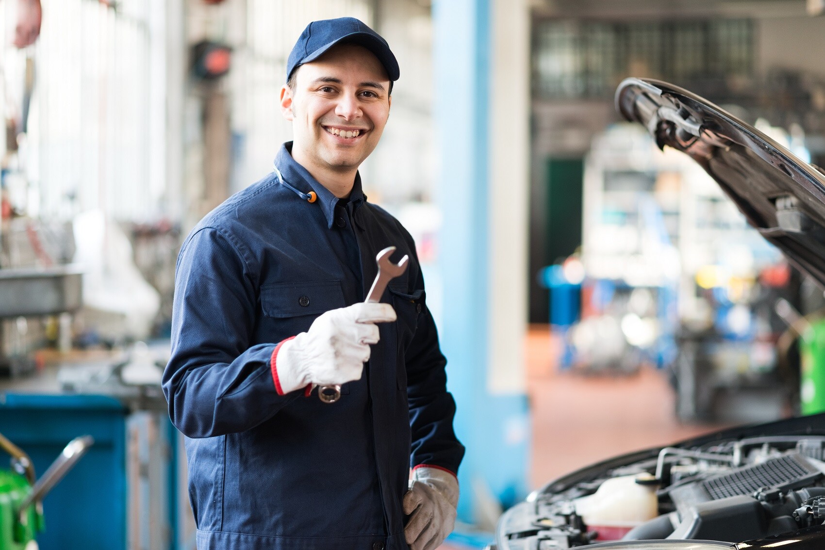 Mechanic holding a wrench and inspecting car engine