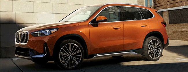 2025 BMW X1 xDrive28i in orange parked outside near Thompson BMW in Doylestown, PA