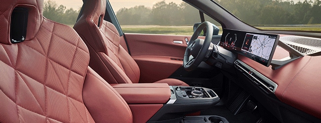 BMW iX interior with red leather seats, curved digital display, and minimalist cabin layout