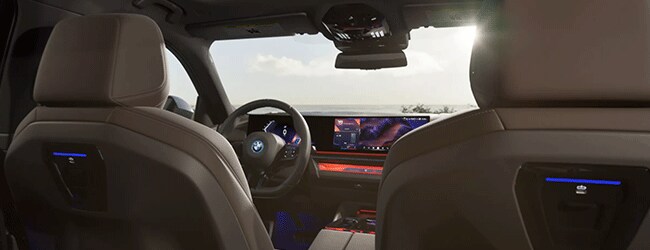 2025 BMW i5 interior with curved display and ambient lighting, seen from back seat