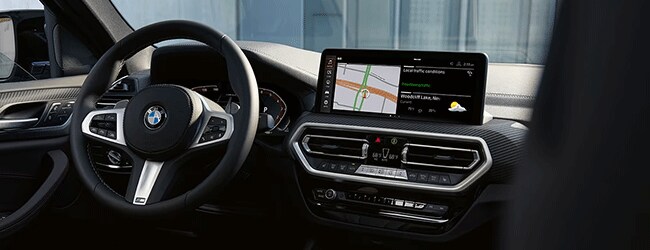 BMW interior showing digital navigation system, steering wheel, and detailed climate control layout