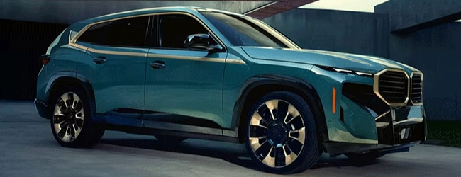 Green BMW XM luxury performance SUV parked near a minimalist concrete structure with bold styling and large M wheels