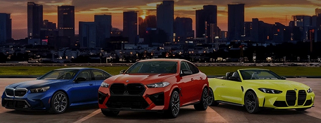2025 BMW M2, XM, and M4 Convertible parked at sunset with city skyline