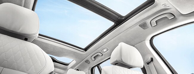 View of BMW panoramic moonroof and quilted white leather interior with ambient daylight