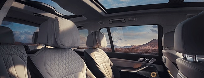Interior of BMW XM with quilted leather seating, large windows, and panoramic sky lounge roof over a scenic desert view