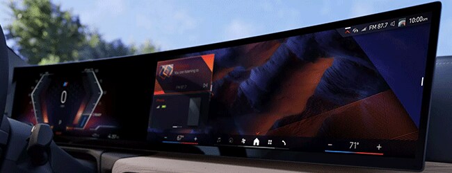 Close-up of BMW Curved Display featuring iDrive 8.5 infotainment with media, navigation, and climate controls