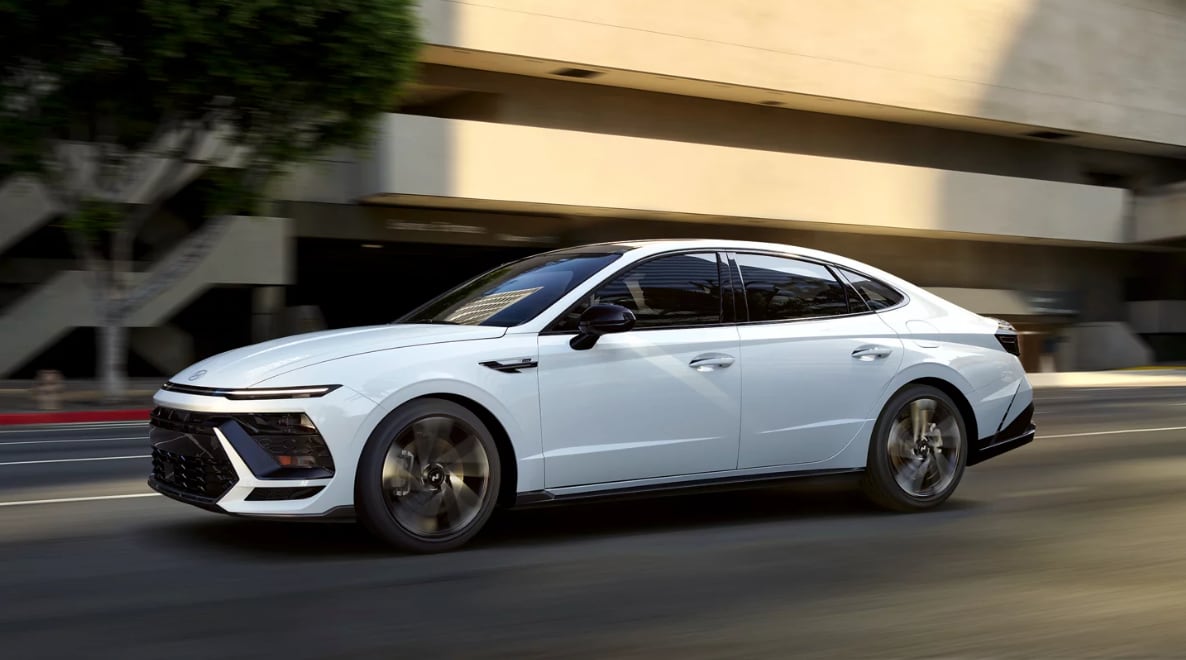 Side view of the 2024 Hyundai Sonata accelerating on a road Side view of the 2024 Hyundai Sonata accelerating on a road