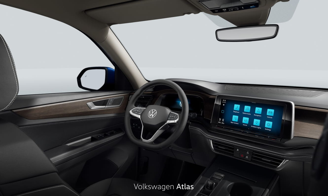 Volkswagen Atlas interior featuring a digital driver display, touchscreen infotainment system, and wood trim on a light gray studio background.