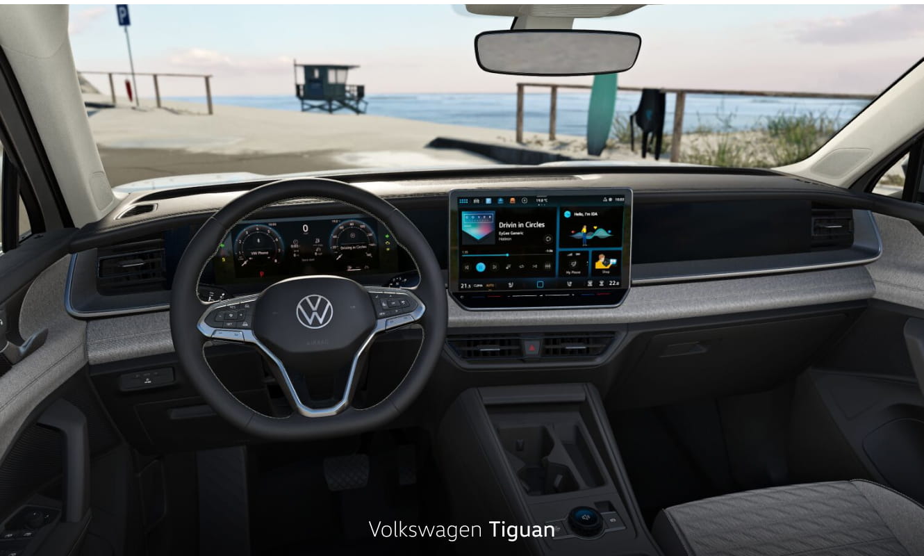 Volkswagen Tiguan interior featuring a digital driver display and touchscreen infotainment system with a beach and ocean view through the windshield.