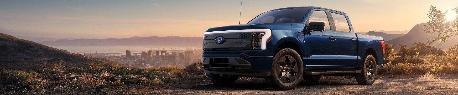 Blue Ford F-150 Lightning electric pickup truck at sunset