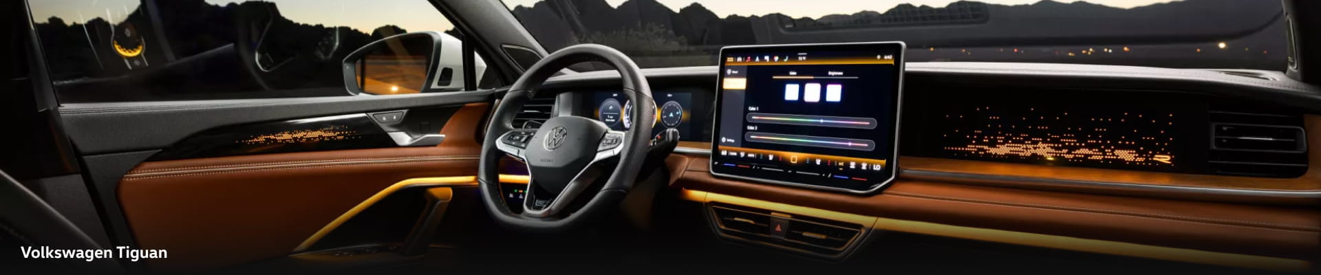 Interior of a Volkswagen Tiguan, featuring a sleek dashboard, illuminated digital display, ambient lighting, and a mountain view through the window.