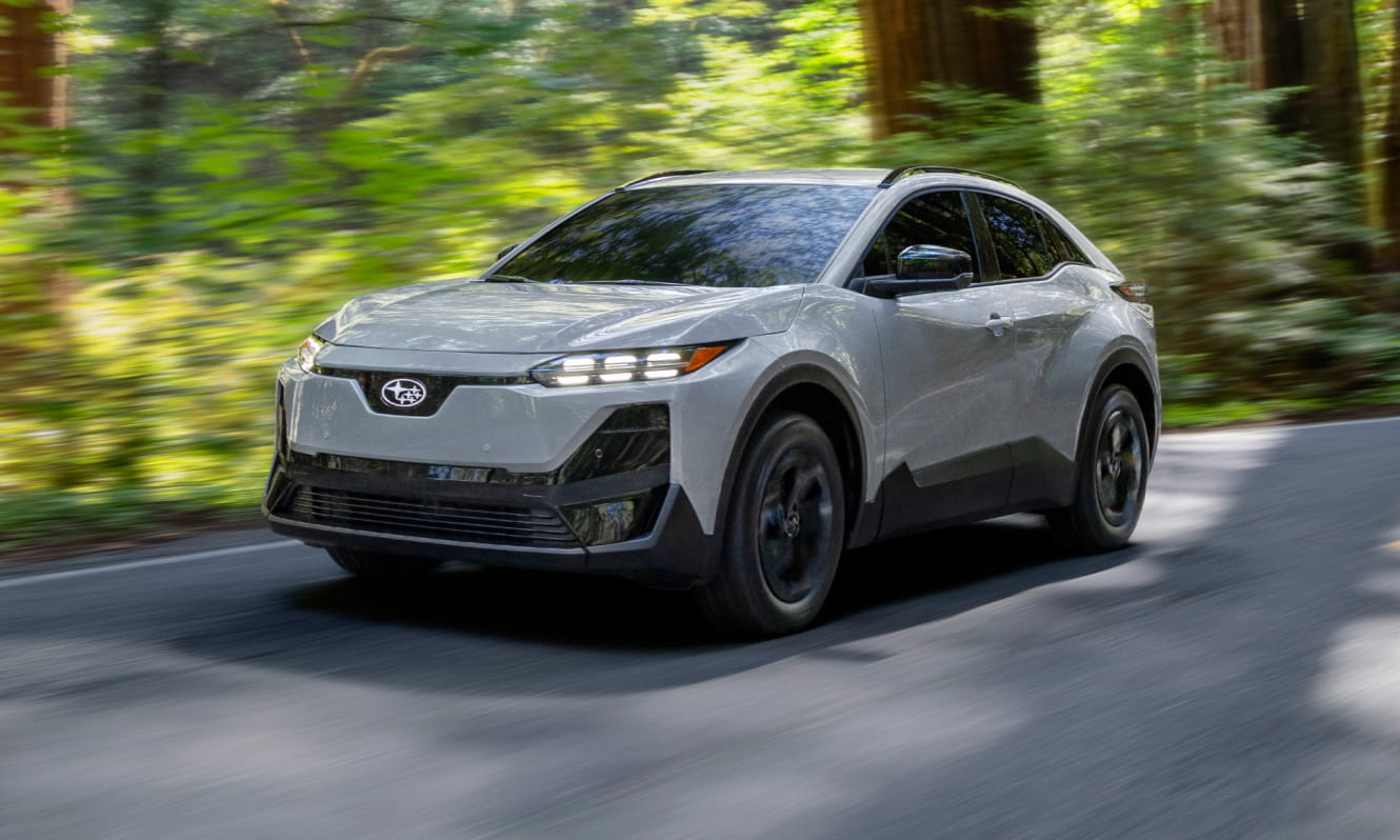 A sleek 2026 Subaru Uncharted drives swiftly along a curving forest road.