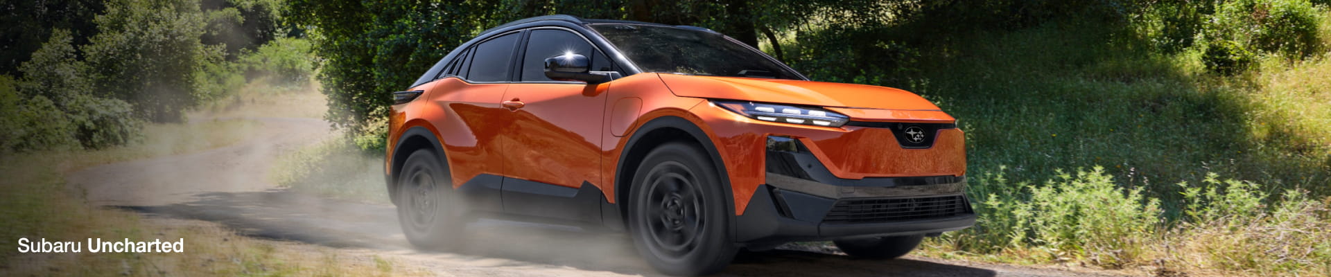 2026 Subaru Uncharted driving on a sandy path through a lush forest.