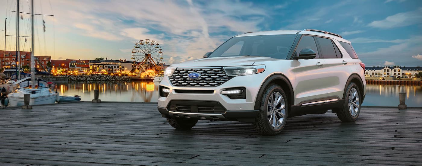 2021 Ford Explorer Pier Clouds.jpg A white 2021 Ford Explorer is parked on a pier in front of a carnival.