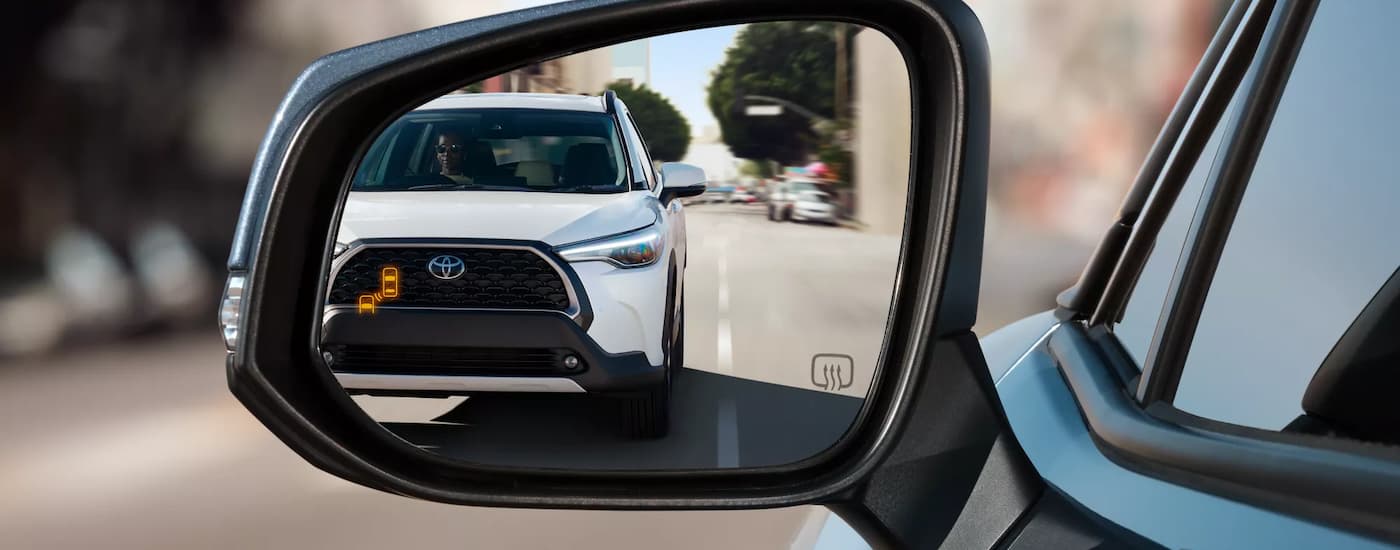 Toyota%20dealer%20near%20Clarksville%20-%202022%20Toyota%20Corolla%20Cross%20XLE%20-%20Mirror.jpg A white 2022 Toyota Corolla Cross XLE driving.