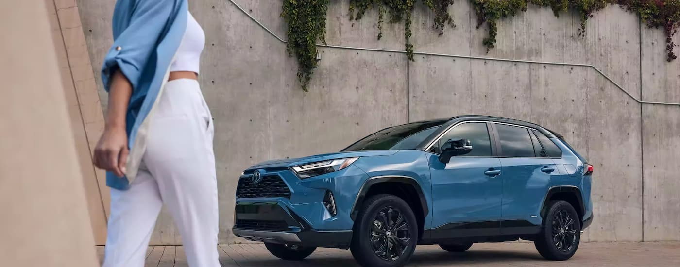 Toyota RAV4 Hybrid for Sale - 2023 Toyota RAV4 Hybrid  - Blue Concrete Wall.jpg A blue 2023 Toyota RAV4 Hybrid is shown parked next to a concrete wall.