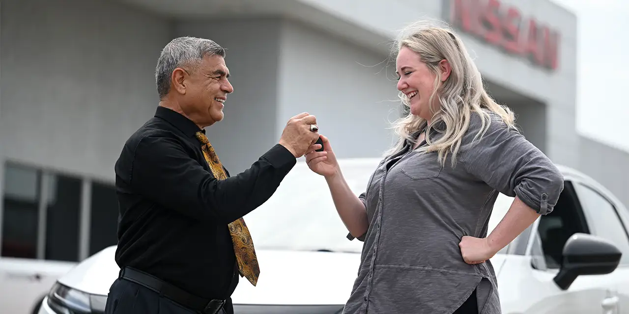 A sales consultant hands car keys to a customer