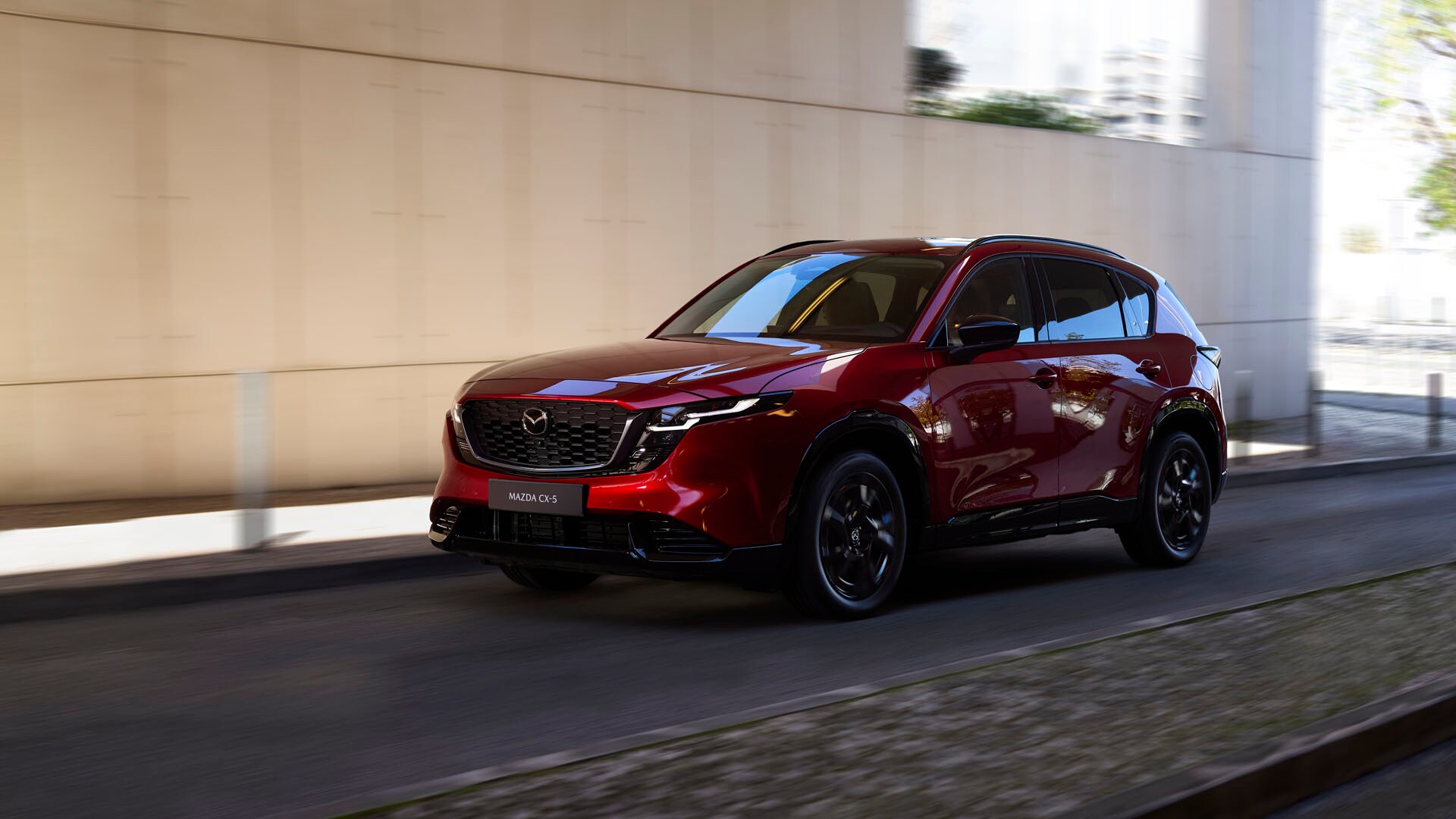 The new 2026 Mazda CX-5 driving on a road next to a building