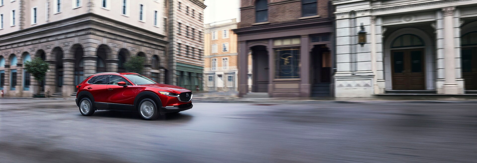 The new 2026 Mazda CX-30 driving on an open road through a city