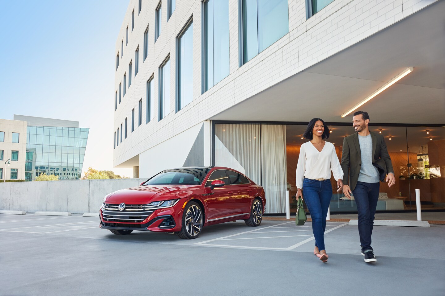 couple walking away from a red Volkswagen Arteon parked at a hotel