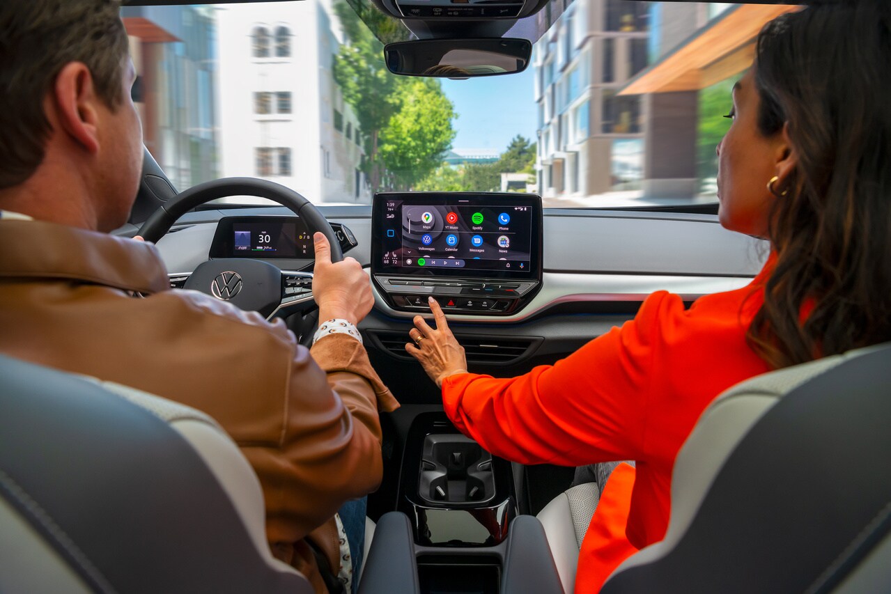 Volkswagen ID.4 interior, passenger using the touchscreen infotainment system