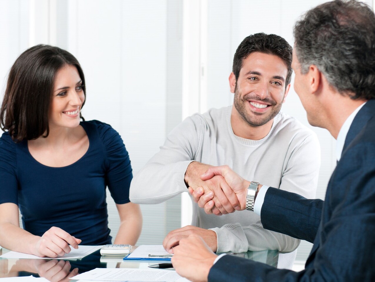 couple shaking hands with a financing team member at a dealership