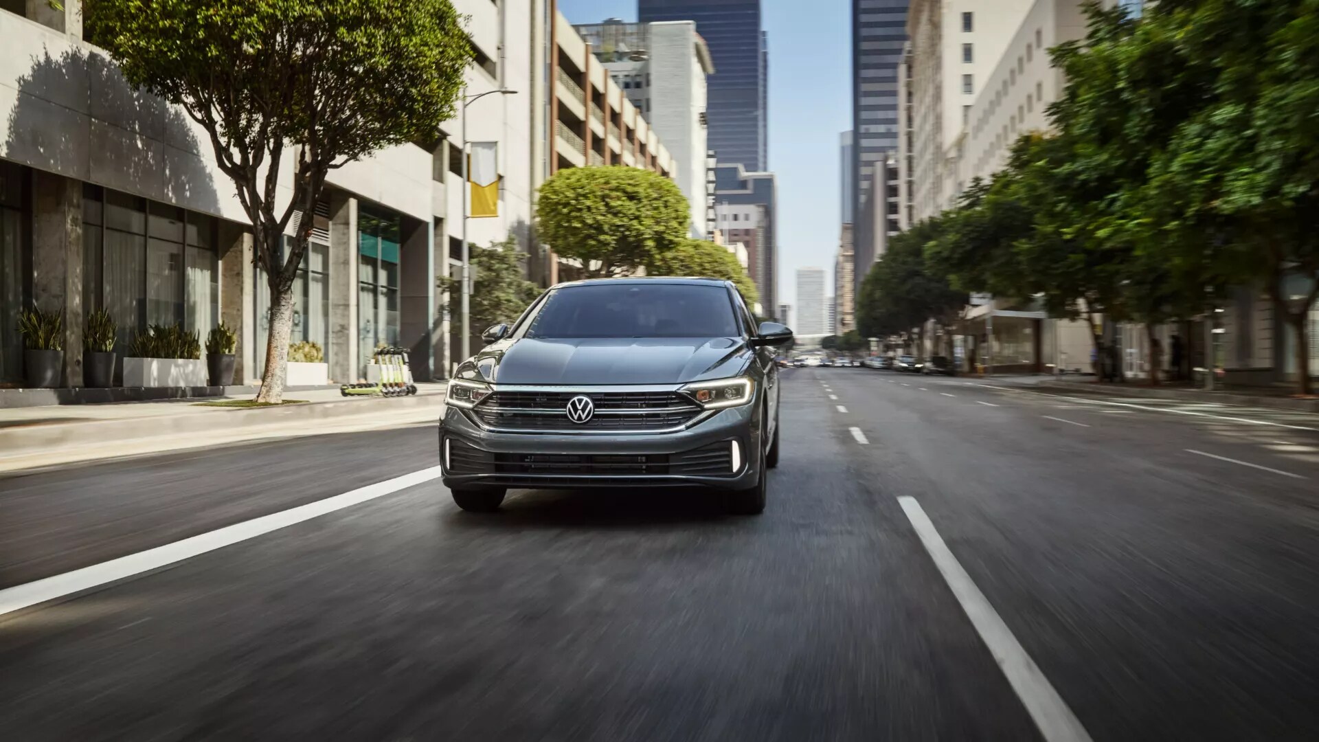 grey Volkswagen Jetta driving down a city street, grill featured