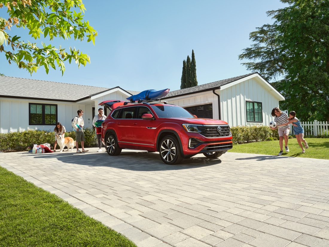 2024-Volkswagen-Atlas-SEL-PremiumRLine-SUV-L03.png red Volkswagen Atlas SUV parked in the driveway of a suburban home
