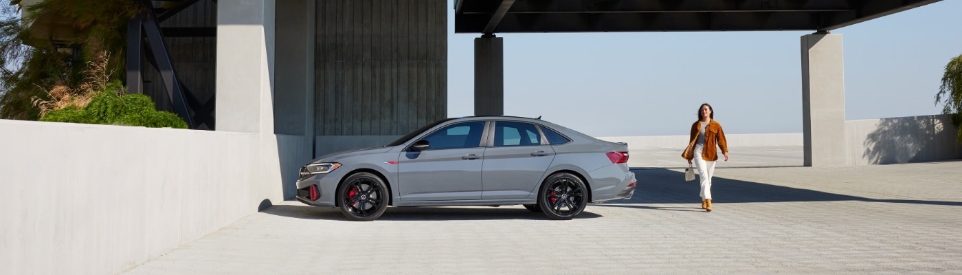 2025 VW Jetta GLI Woman walking away from a parked VW Jetta GLI