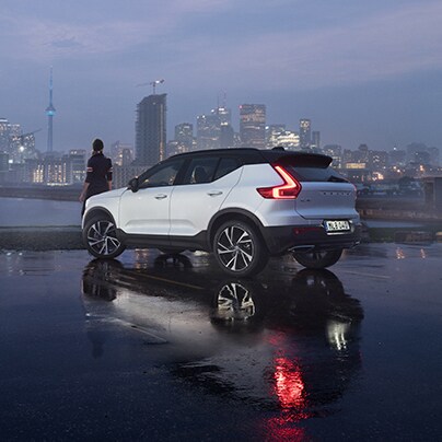 Volvo Cars New Bern is a Volvo Dealership in New Bern near Greenville NC | White Volvo MY20 XC40 parked in parking lot in front of city and bay at dusk with fog