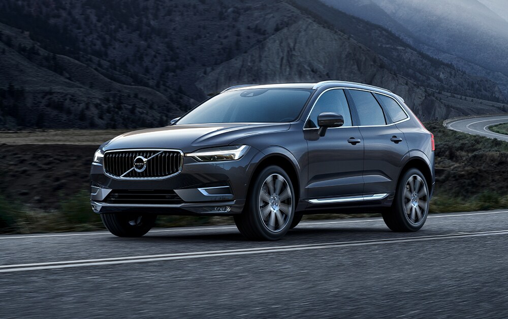 Volvo of New Bern is a Car Dealership in New Bern near Trent Woods, NC | Silver 2020 Volvo XC60 Driving Down Mountainside Road Volvo of New Bern is a Car Dealership in New Bern near Trent Woods, NC | Silver 2020 Volvo XC60 Driving Down Mountainside Road