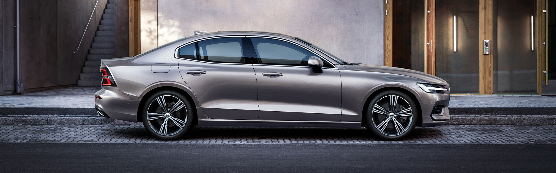 Volvo Cars New Bern is a Car Dealership near Beaufort NC | Beige 2020 S60 Parked in Front of House in City Volvo Cars New Bern is a Car Dealership near Beaufort NC | Beige 2020 S60 Parked in Front of House in City