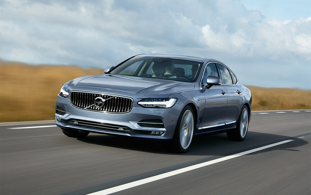 Volvo of New Bern is a Car Dealership in New Bern near Trent Woods, NC | Silver 2020 Volvo S90 Driving Down Road Volvo of New Bern is a Car Dealership in New Bern near Trent Woods, NC | Silver 2020 Volvo S90 Driving Down Road
