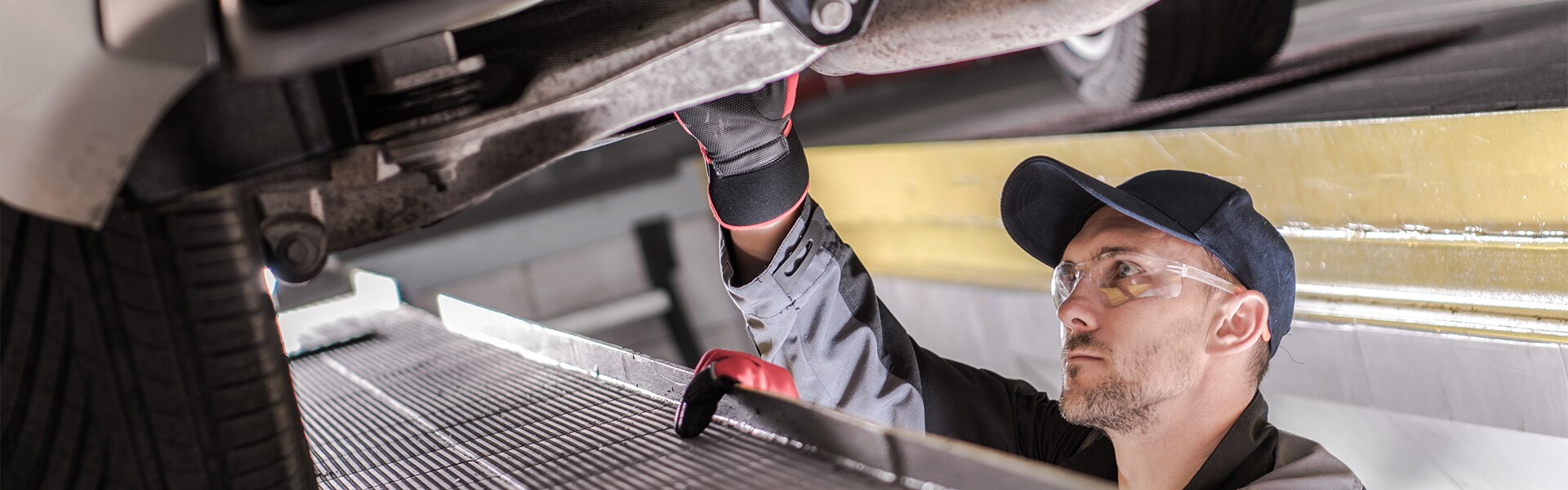 Volvo of New Bern is a Car Dealership in New Bern near Trent Woods, NC | Service Advisor Working on Undercarriage of Car Volvo of New Bern is a Car Dealership in New Bern near Trent Woods, NC | Service Advisor Working on Undercarriage of Car