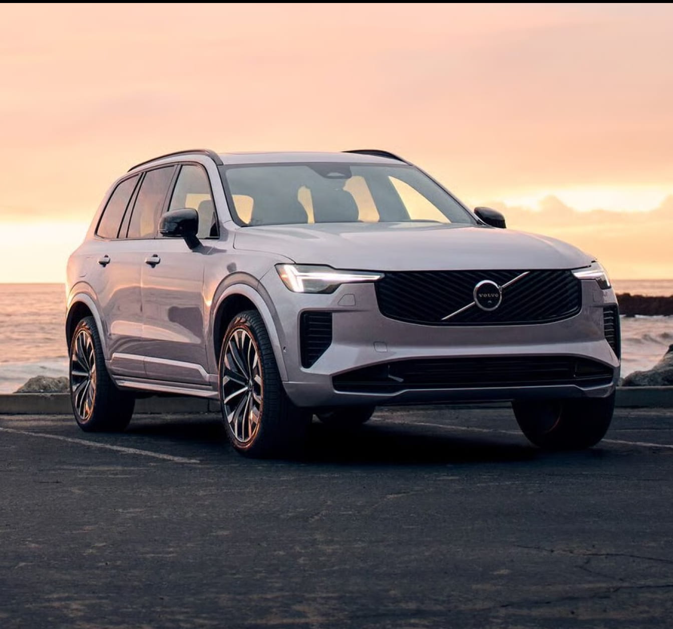 Volvo XC90 parked near the water at sunset, shown from a front three-quarter angle.