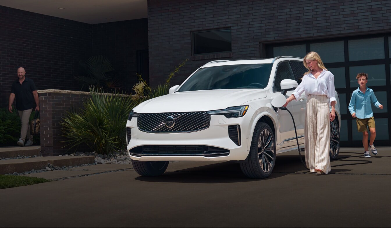 Volvo XC90 Plug-In Hybrid Ultra charging in a modern suburban driveway.