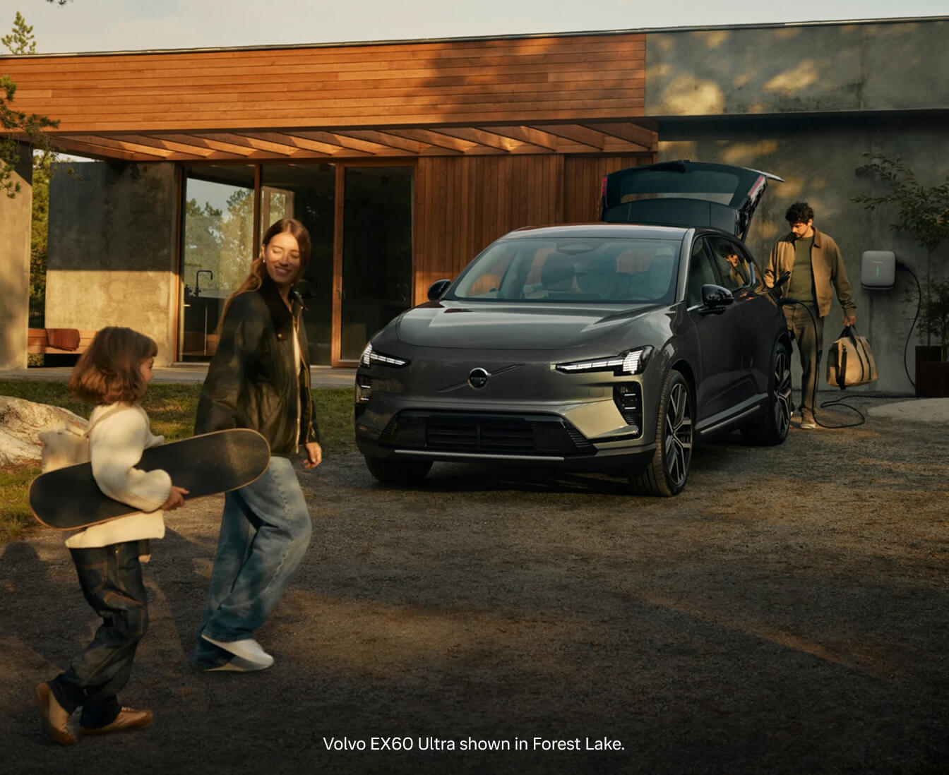 Front three-quarter view of a 2026 Volvo EX60 Ultra in Forest Lake parked in a paved gravel driveway in front of a modern home.