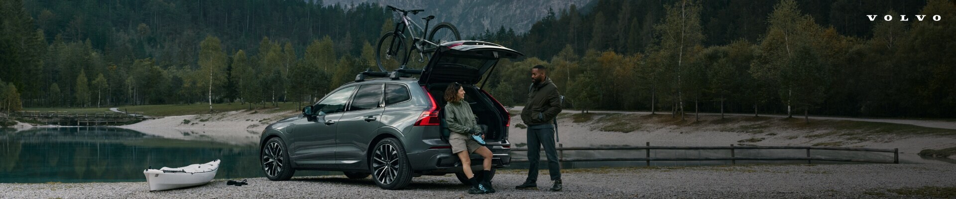 Rear-three-quarter profile view of a 2026 Grey Volvo XC60 Ultra with a roof-mounted bike parked.