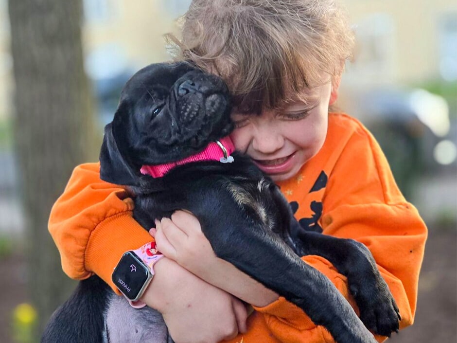 Little girl hugging a black puppy sponsored by W&L Subaru