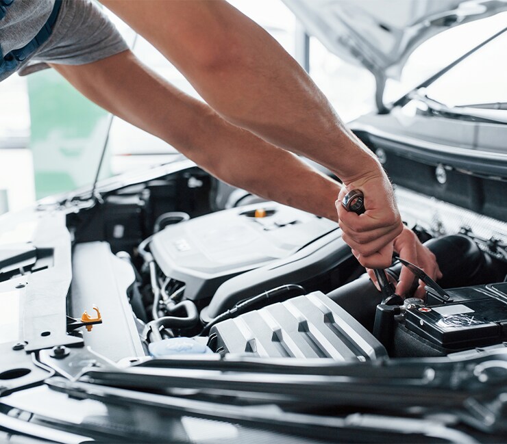 How to Prepare to Trade in Your Car | West Broad Hyundai in Henrico, VA | Mechanic tightening car battery in the engine bay