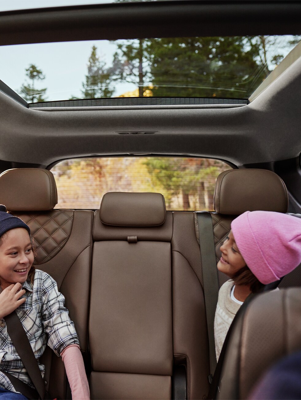 2023 Hyundai Santa Fe at West Broad Hyundai | Two children laughing and looking at each other in the backseat of a 2023 Santa Fe