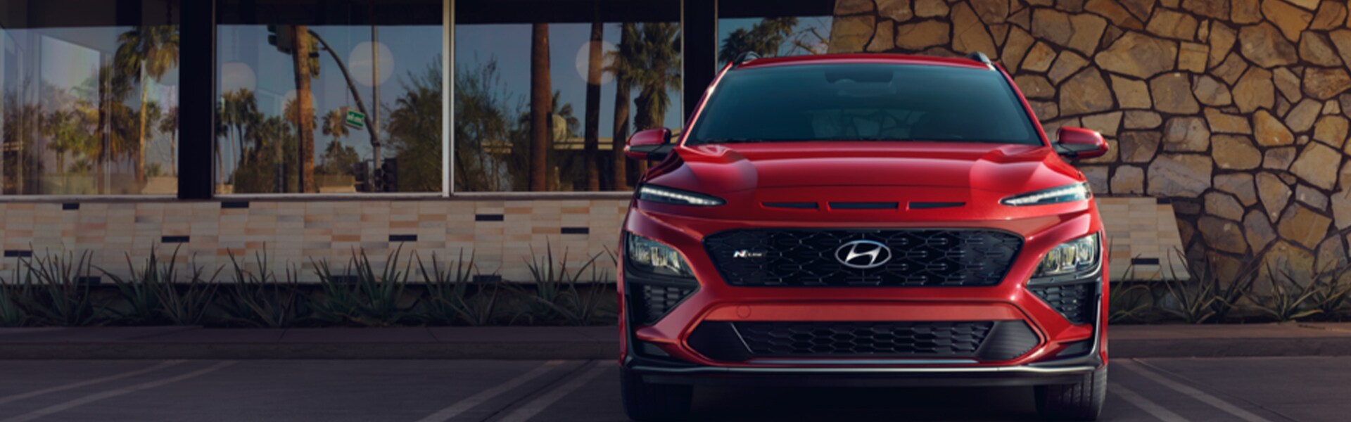 Performance features of the 2022 KONA Electric at West Broad Hyundai of Henrico | Front end shot of a red 2022 Hyundai Kona in front of a modern house in the desert