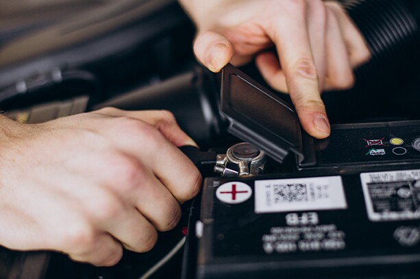 How to prepare your Hyundai for the winter season in Henrico, VA at West Broad Hyundai | Person using their hands to lift battery cover and examine car battery