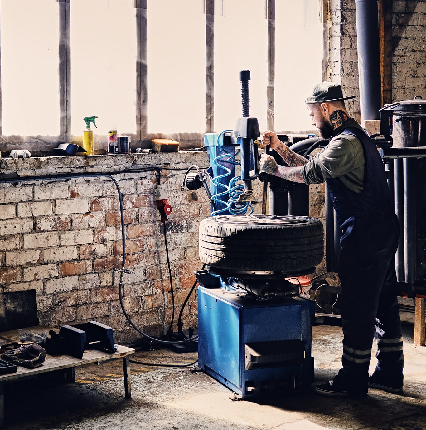 What is Tire and Rim Protection? | West Broad Hyundai | Mechanic in navy blue uniform and black hat is removing the tire off of a car wheel by using a tire remover machine