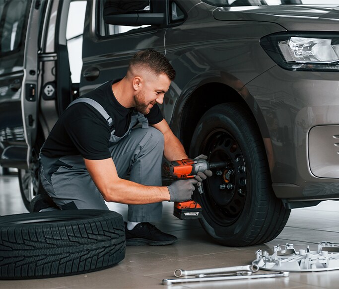 How to Get Your Car Summer Ready at West Broad Hyundai in Henrico, VA | Mechanic using power gun to remove tire from car and replace with another tire